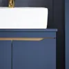 A close-up view of a blue bathroom vanity with a white sink and a gold faucet. Produktbild-Vorschau