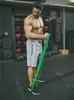 A man is performing a bicep curl with a resistance band in a gym. Náhľad obrázku produktu