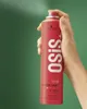 A hand holding a red spray can against a green background. Podgląd zdjęcia produktu