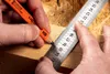 A close-up shot of hands using a ruler and pencil to mark a piece of wood. Podgląd zdjęcia produktu