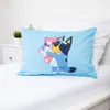 A light blue pillowcase with a cartoon character printed on it, lying on a white bed. Produktbild-Vorschau