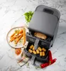 A dual-basket air fryer is shown on a marble countertop, with food items arranged around it. Anteprima dell’immagine prodotto