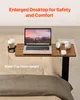 A laptop table is set up on a bed, with a laptop, headphones, a mouse, and a cup of coffee on it. Produktbild-Vorschau