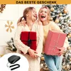 Two women are laughing and holding Christmas gifts in front of a decorated Christmas tree. Produktbild-Vorschau