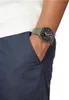 A person's arm wearing a green Casio G-Shock watch with a black face, with their hand in their pocket. Produktbild-Vorschau