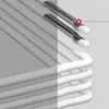 Close-up view of the metallic ends of white hangers, with a red dot highlighting one of them. Náhľad obrázku produktu