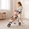 A young girl is playing with a doll in a stroller indoors. Náhľad obrázku produktu