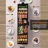 A flat lay image showing an electric grill with various foods arranged on it and around it, along with plates of food and cutlery. Voir les images du produit