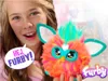 A young girl is holding a colorful Furby toy. Podgląd zdjęcia produktu