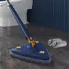 Dunkelblauer dreieckiger Mopp mit grauem Mikrofaser-Kopf auf dunklem Fliesenboden neben einer Toilette, mit zwei zusätzlichen Mopp-Bezügen Produktbild-Vorschau