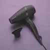 A black hairdryer with a purple accent and a nozzle attachment is placed on a purple surface. Náhled obrázku produktu