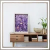 A framed artwork filled with purple floral elements is displayed on a wooden console table. Anteprima dell’immagine prodotto