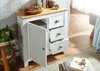 A white sideboard with a wooden top, featuring three open drawers and one closed door, is placed in a room with a brick wall and wooden floor. Podgląd zdjęcia produktu