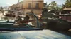 A person is leaning out of a car, reaching towards a tank in a street scene. Podgląd zdjęcia produktu