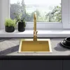 A modern kitchen sink with a gold faucet, set against a window with a view of greenery. Podgląd zdjęcia produktu