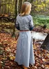 A young girl wearing a medieval-style dress stands in a forest during autumn. Produktbild-Vorschau