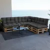 A sectional sofa made of wooden pallets with dark grey cushions is placed on a balcony overlooking the ocean. Anteprima dell’immagine prodotto