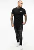A man wearing a black t-shirt and black jeans, standing against a white background. Produktbild-Vorschau