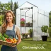 A woman is holding a basket of vegetables in front of a greenhouse. Produktbild-Vorschau