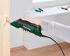 A person is using an electric scraper tool on a wooden surface near a window. Produktbild-Vorschau