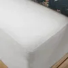 A close-up view of a white jersey bed sheet, folded at the corner, with a dark patterned fabric visible at the top edge. Náhľad obrázku produktu
