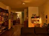 A view of a living room and kitchen area with a desk and bookshelves. Voir les images du produit