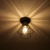 A vintage-style ceiling light fixture with a diamond-shaped metal cage and a visible Edison-style bulb, casting dramatic shadows on the ceiling. Produktbild-Vorschau
