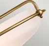 Close-up of a brass-colored metal frame and a white glass shade of a ceiling lamp. Produktbild-Vorschau