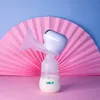 A breast pump sits on a pink surface in front of a pink fan-shaped backdrop, with a light blue background above. Podgląd zdjęcia produktu