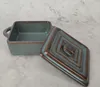 A square ceramic baking dish with its lid slightly ajar, placed on a textured surface. Náhled obrázku produktu