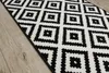 A close-up view of a black and white geometric patterned rug on a wooden floor. Anteprima dell’immagine prodotto
