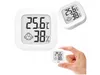 A digital thermometer and hygrometer is shown in different sizes and perspectives, with one being held by a hand. Podgląd zdjęcia produktu