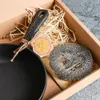 A cast iron skillet and a scrubber presented in a box with straw. Produktbild-Vorschau