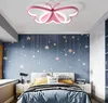 A bedroom with a butterfly-shaped ceiling lamp, star-themed wallpaper, and a bed. Náhled obrázku produktu