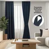 A living room scene with navy blue curtains tied back, a sheer curtain behind them, and a coffee table in the foreground. Produktbild-Vorschau