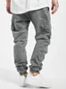 A person wearing gray cargo jogging pants and white sneakers. Produktbild-Vorschau