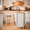 A modern kitchen with white cabinets, a wooden countertop island, and bar stools. Náhľad obrázku produktu