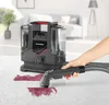 A hand is using a carpet cleaner to remove a red stain from a white carpet in a living room. Produktbild-Vorschau