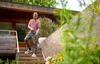 A man is using a pressure washer on outdoor stairs next to a house. Produktbild-Vorschau