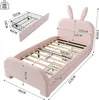 A pink children's bed with bunny ears on the headboard, shown with dimensions and an accessory basket. Voir les images du produit
