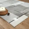 A close-up view of a rug with a geometric pattern on a wooden floor, with a basket and a pinecone on the rug. Produktbild-Vorschau