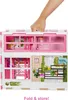 A hand is holding the handle of a folded Barbie dollhouse. Produktbild-Vorschau