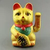 A golden Maneki Neko cat figurine with red ears and collar, and a green glittery chest, sits against a plain gray background. Produktbild-Vorschau