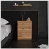 A close-up view of a wooden nightstand next to a bed in a bedroom. Produktbild-Vorschau