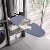 A pull-out ironing board is shown extended from a closet, with an iron and a piece of fabric on it. A washing machine is visible to the left, and a window with greenery is in the background. Podgląd zdjęcia produktu
