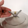 A hand is shown adjusting the wing nut on a stainless steel lid of a container. Produktbild-Vorschau