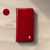 A red leather phone case with a bull logo is displayed on a textured surface. Produktbild-Vorschau