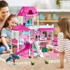 A mother and two daughters are playing with a large pink dollhouse. Voir les images du produit