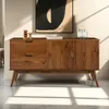 A wooden sideboard with drawers and doors, displayed in a room with natural light casting shadows. Produktbild-Vorschau