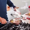A person is cooking food in a pan on a stovetop. Anteprima dell’immagine prodotto